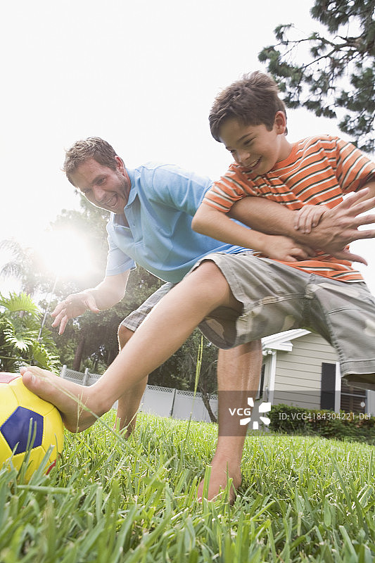 父亲和儿子在后院踢足球图片素材