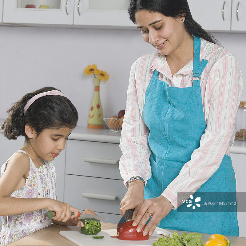 中年妇女和她的女儿在厨房的砧板上切蔬菜图片素材