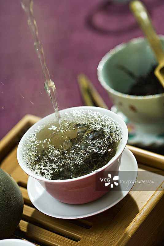 热水倒在茶杯里，溅在茶叶上图片素材