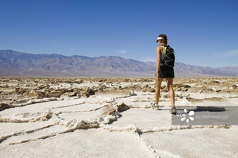 美国犹他州博纳维尔盐滩，一名妇女行走在龟裂的沙漠景观中图片素材