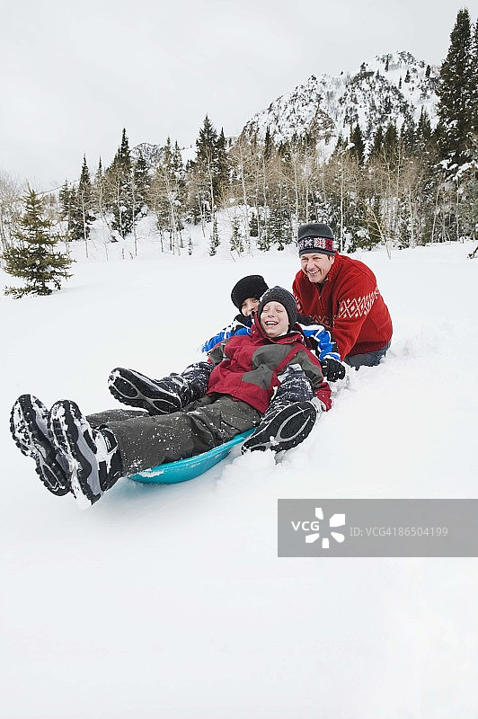 父亲推着儿子坐雪橇图片素材