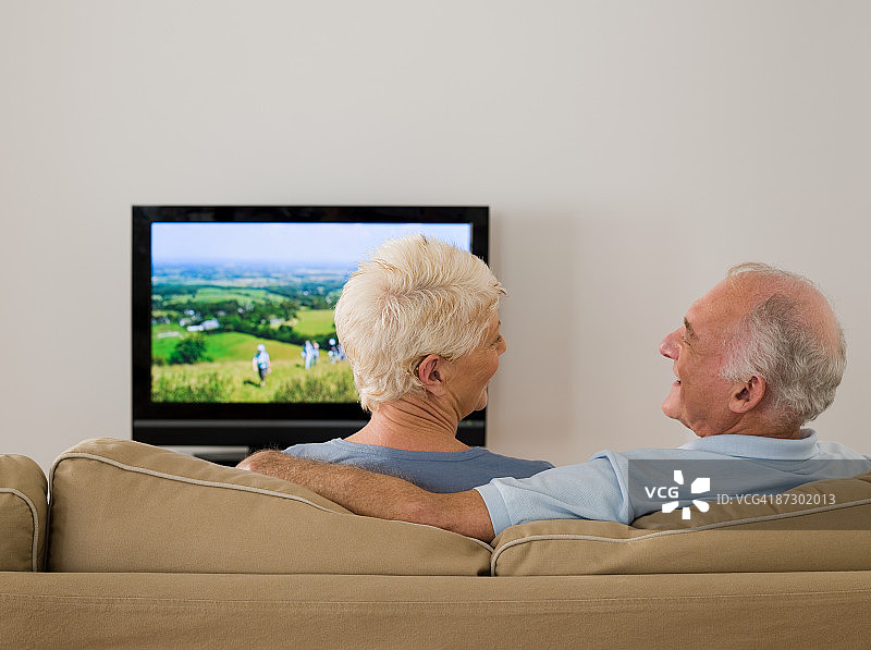 一对老年夫妇一边看电视一边聊天图片素材