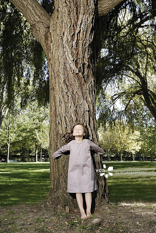 一个5岁的女孩站在一棵树旁图片素材
