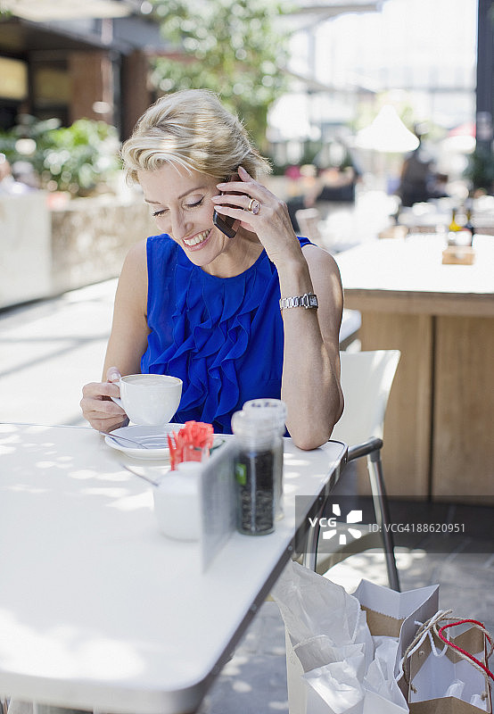 一个女人一边在咖啡馆喝咖啡一边打电话图片素材
