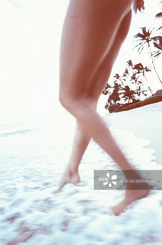 女人的腿在海浪上行走，低角度视图，瓦胡岛，夏威夷，美国图片素材