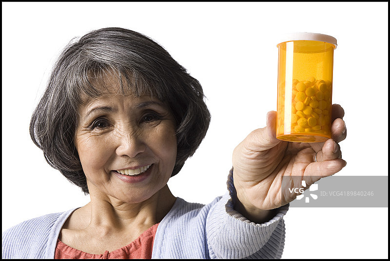 老妇人拿着一瓶药丸图片素材