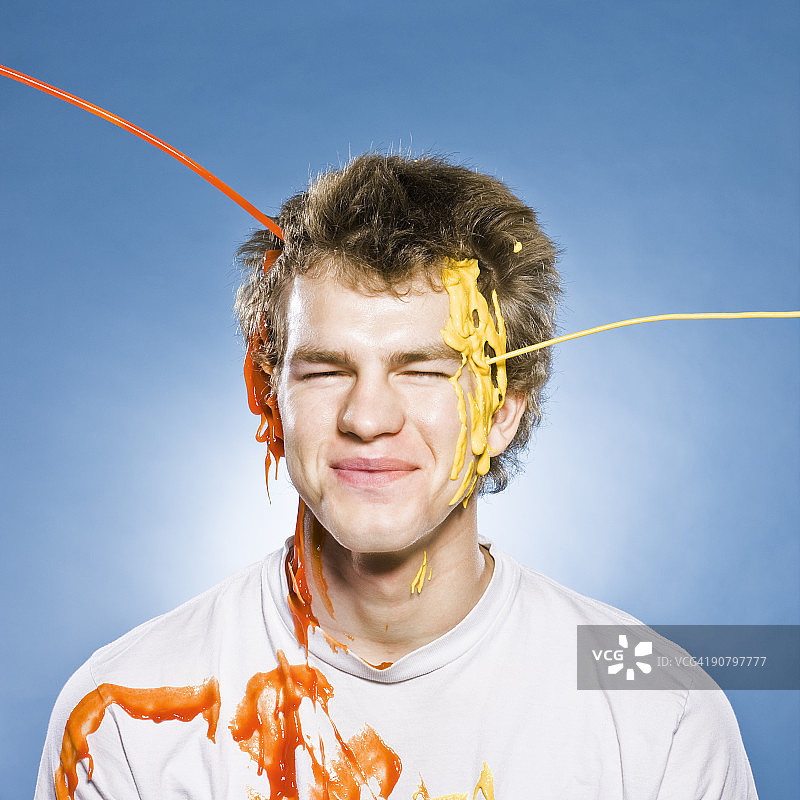 一个被番茄酱和芥末倒在头上的男人图片素材