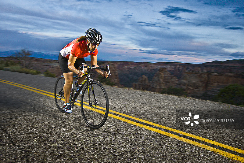 侧面的女性骑自行车在道路上在黄昏图片素材