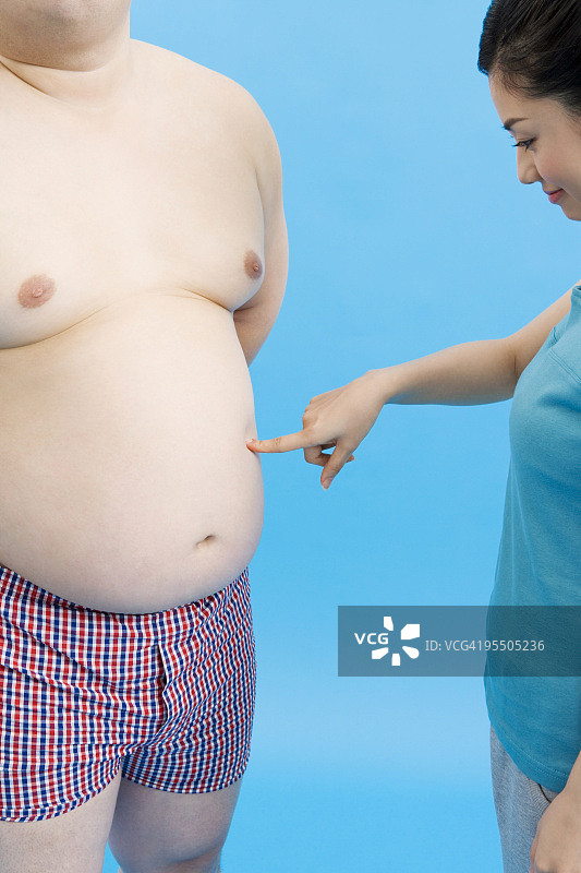 一个女人摸着一个胖男人的肚子图片素材