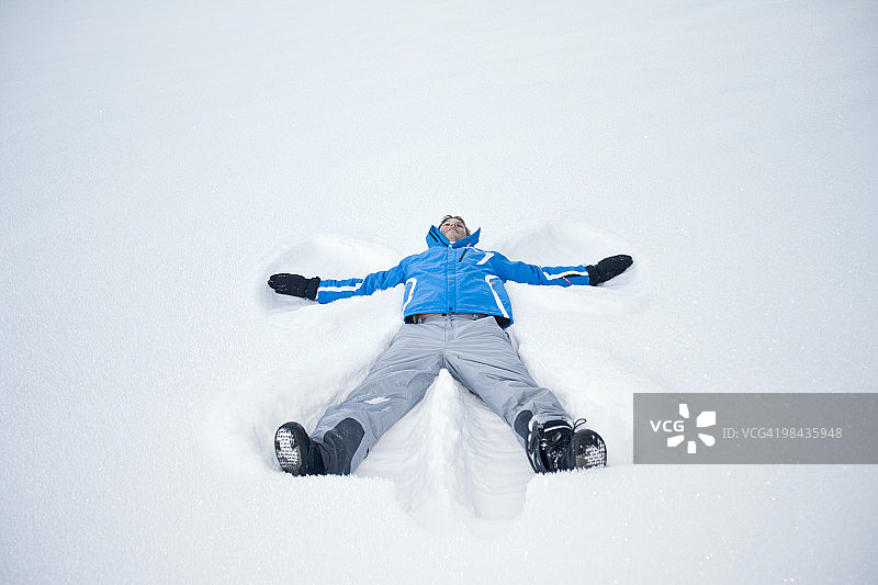 年轻人躺在雪地里做雪天使图片素材