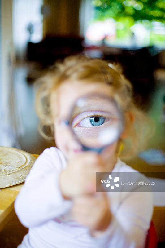 蓝眼睛蹒跚学步的小女孩拿着放大镜图片素材
