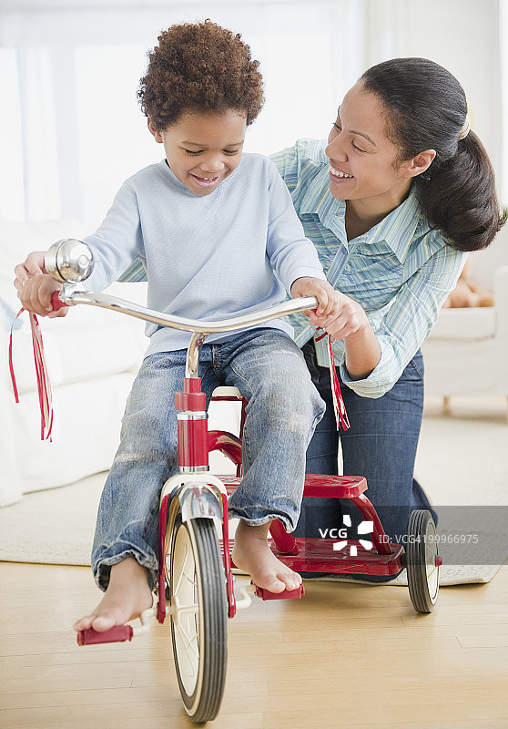 混血妇女教儿子骑三轮车图片素材