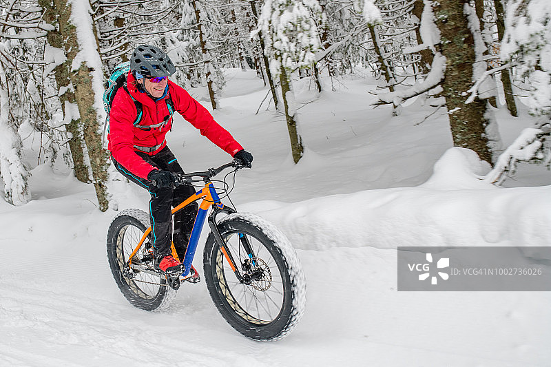 一个胖子在雪地上骑自行车穿过冬天的森林图片素材