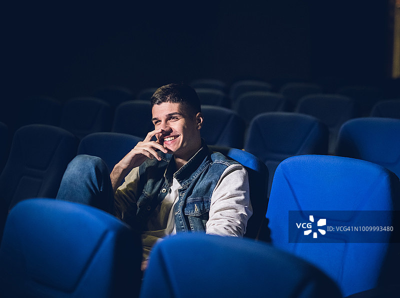 年轻的白人男子在电影院看电影和放松的自由时间。图片素材