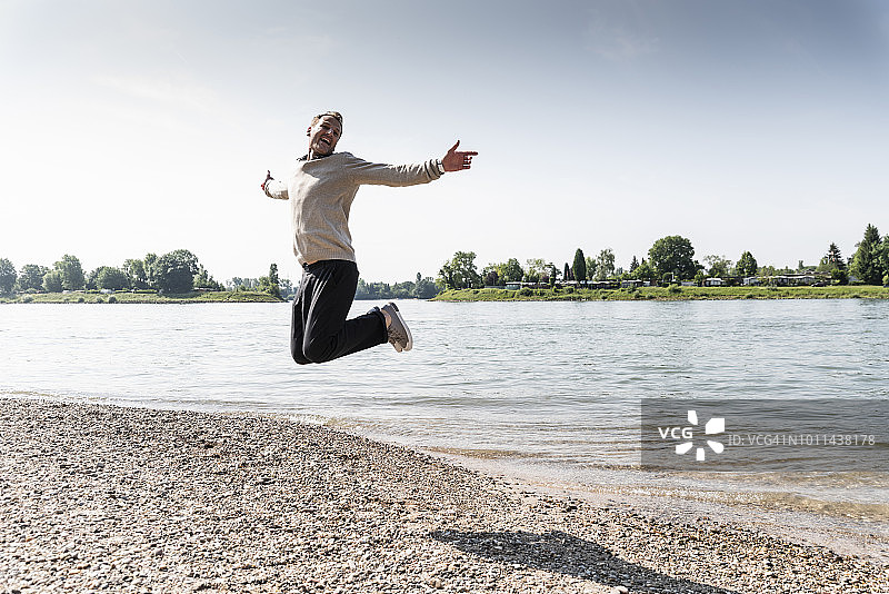 一个成熟的男人在莱茵河岸边的空中跳跃图片素材
