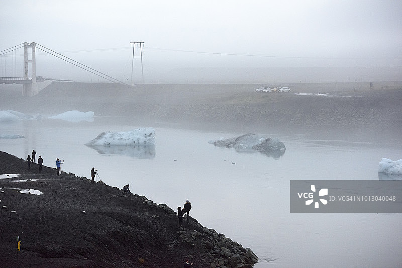 一群人在Jökulsárlón冰川湖，桥在冰岛东部地区的雾图片素材