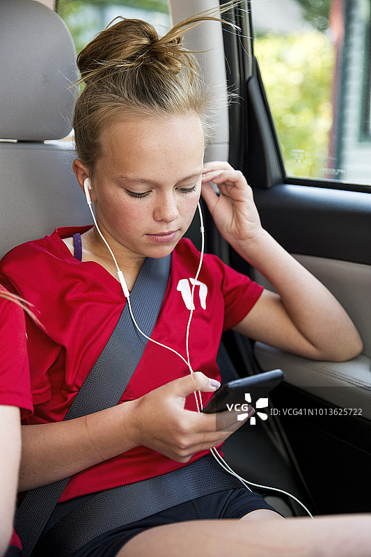 女孩在车里用智能手机听音乐图片素材