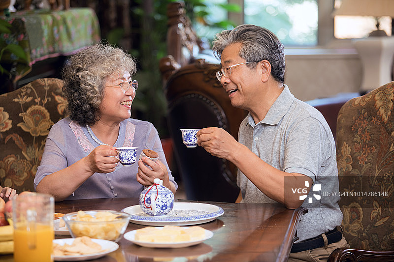 亚洲祖父母一起在客厅喝下午茶。图片素材