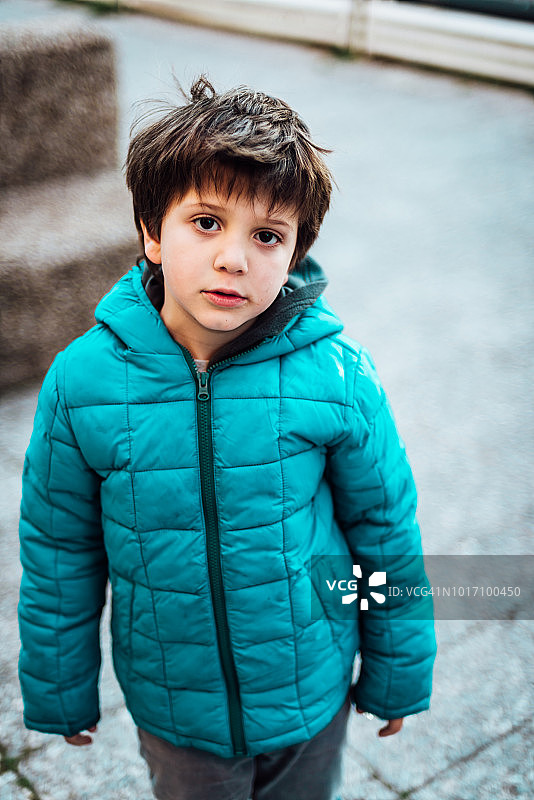 可爱的小男孩穿着蓝色的外套在外面玩图片素材