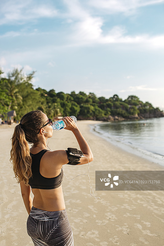 泰国，帕岸，一个在海滩上喝水的女人图片素材