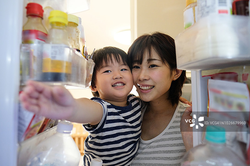 家庭主妇抱着孩子打开冰箱门图片素材
