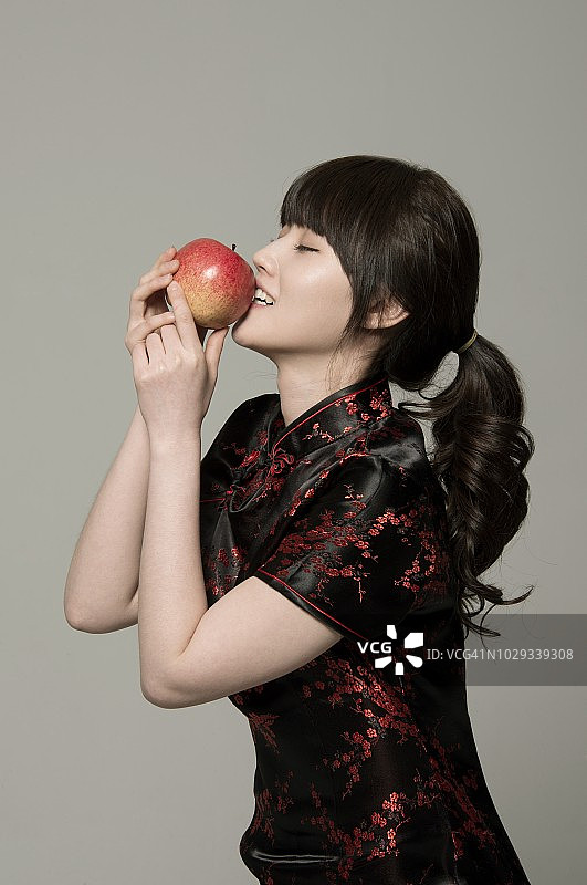 穿着中式服装的年轻女子在吃苹果图片素材