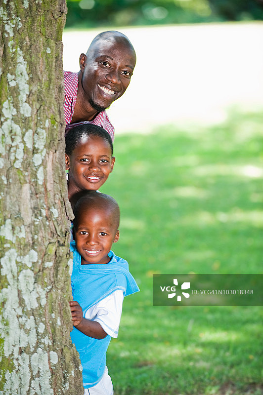 父亲和孩子(4-8岁)从树后窥视的肖像，约翰内斯堡，豪登省，南非图片素材