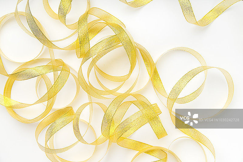 闪亮的金色丝带缠绕在白色背景的螺旋图案。文本或公告的背景图片素材