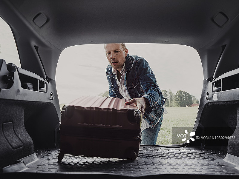 一个男人在他的车里打包他的行李箱准备公路旅行图片素材