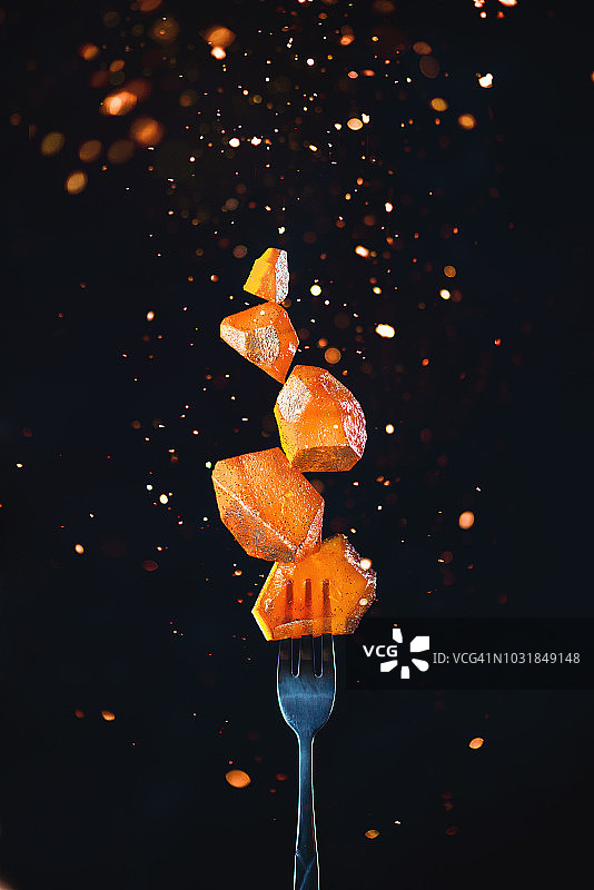 叉子上放着金色的果酱块，上面有火花和闪光。行动食物摄影在一个黑暗的背景与复制空间。美味甜点的概念。图片素材