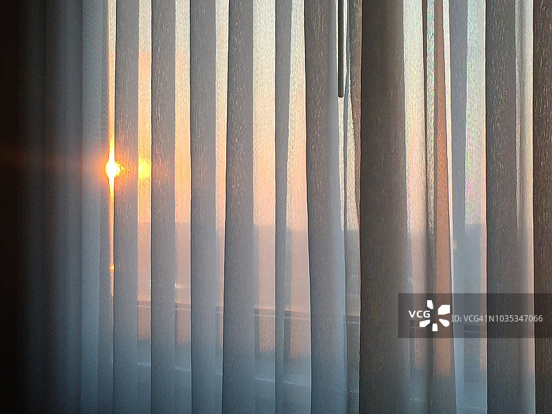 神奇时光:日出时透过褶皱的滑动窗帘图片素材
