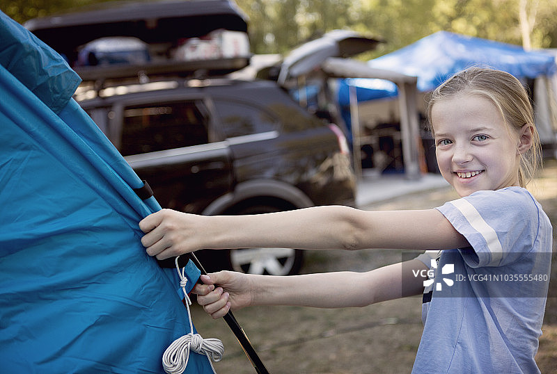 微笑的女孩在营地组装帐篷图片素材