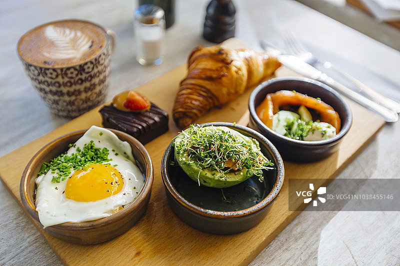 咖啡厅的早餐配煎蛋、牛油果、三文鱼、牛角面包和咖啡图片素材