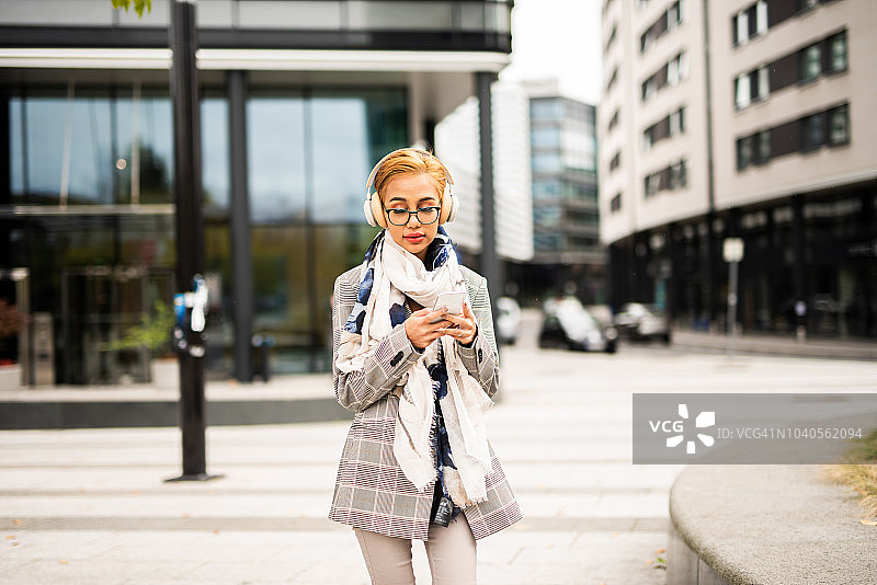 年轻女性在城市中使用智能手机。图片素材