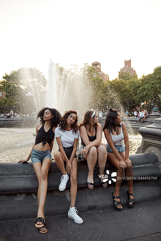 年轻女性在城市公园的喷泉旁闲逛图片素材