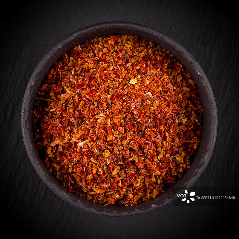 粉碎的红辣椒在石头碗在黑暗的背景图片素材