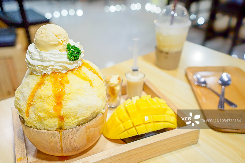托盘上的芒果冰苏，或Bingsoo(韩国食物)芒果加甜炼乳和冰淇淋在木桌上图片素材