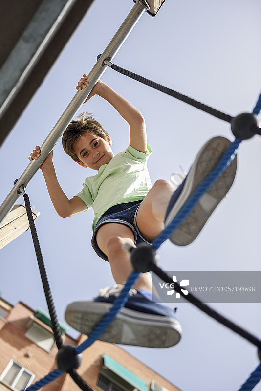 微笑的小女孩在攀爬架上的肖像图片素材