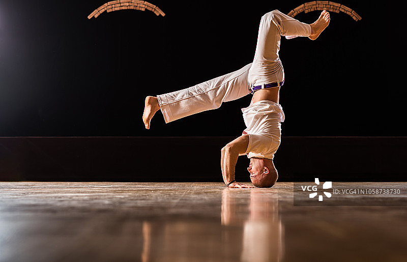 卡波耶拉舞运动员在健身俱乐部的地板上练习倒立。图片素材