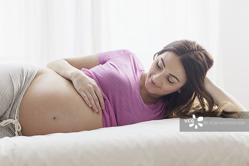 孕妇在床上摸肚子图片素材