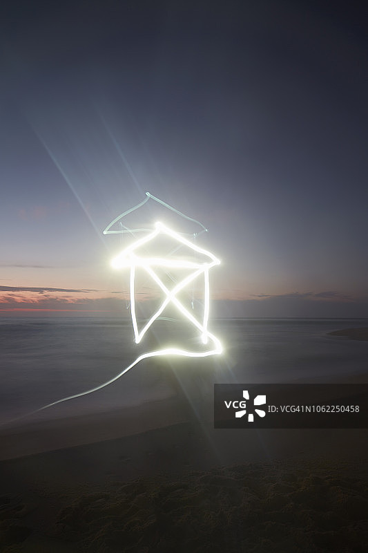 日落时海滩上房屋形状的光迹(光绘)图片素材