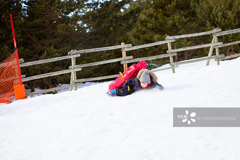 一个男孩用雪橇拉下一座雪山图片素材