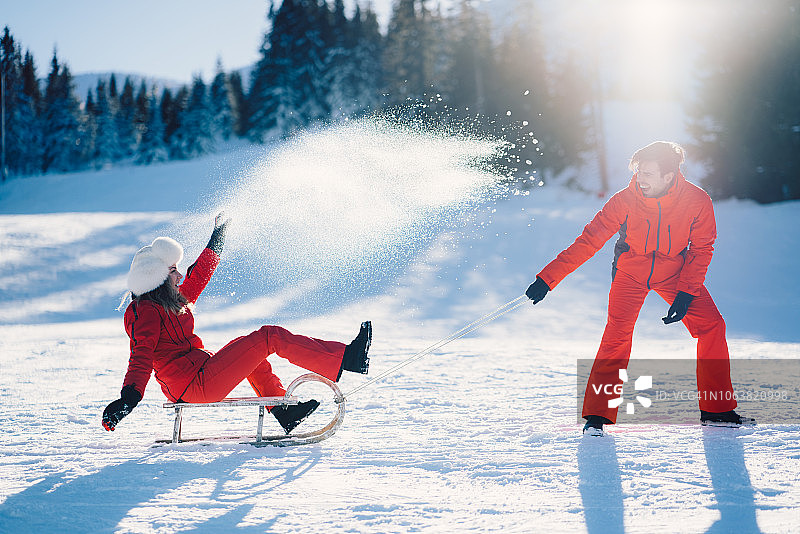 一对快乐的夫妇在寒假里玩雪橇图片素材