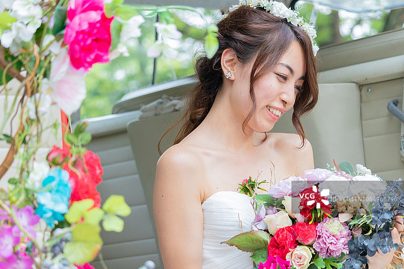 日本新娘微笑着，看着车座上的花束图片素材