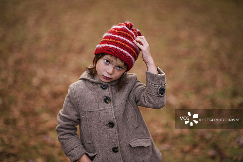 一个女孩站在树林里，手放在头上的肖像，美国图片素材