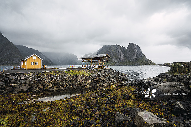 挪威，罗浮敦，岩石海岸上遥远的黄色房子图片素材