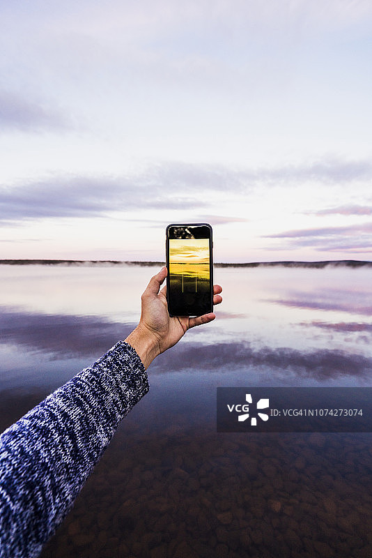 瑞典，拉普兰，用智能手机拍摄日落的人图片素材