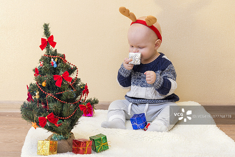 可爱的小鹿宝宝坐在圣诞树旁，带着礼物图片素材