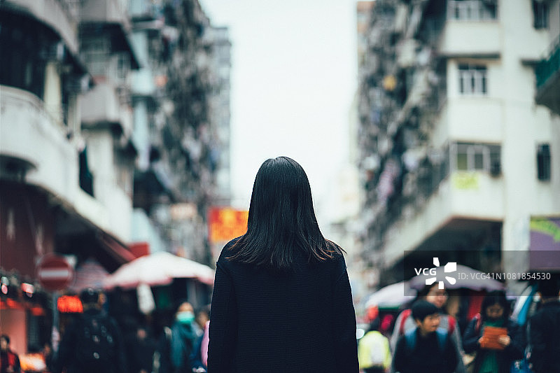后视图的女人走在繁忙的当地城市街道，被古老的传统建筑和迷失在城市图片素材