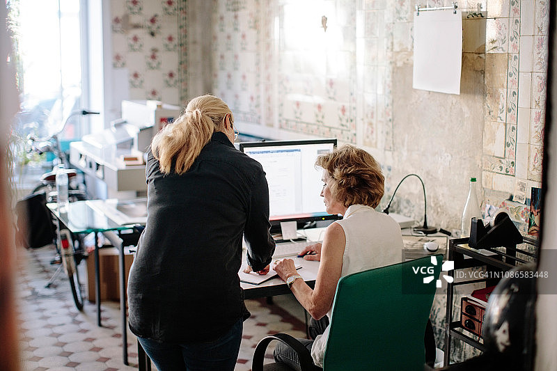 女性设计专业人士在设计工作室的办公桌上讨论图片素材